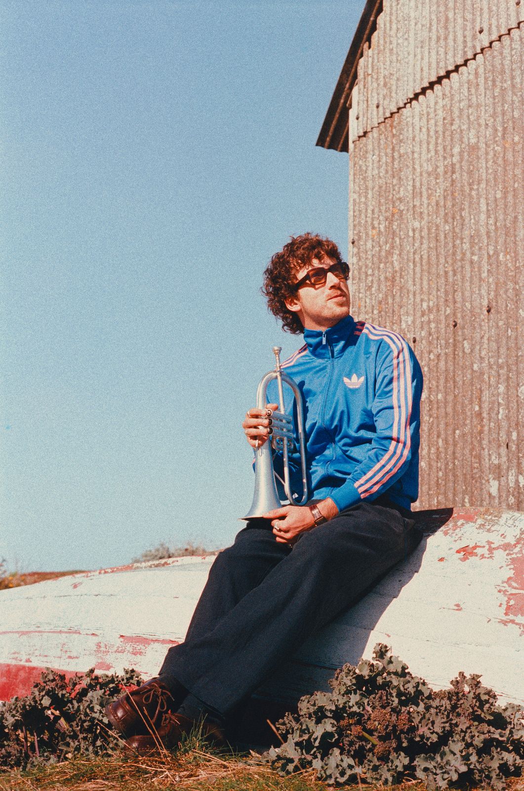 Sol Paradise holding a trumpet on a shingle beach